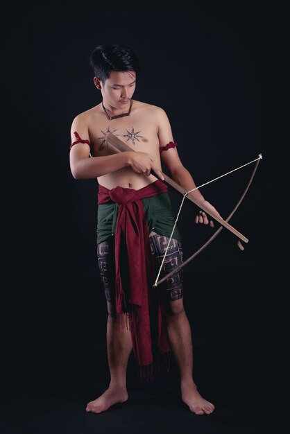 young THAILAND male warrior posing in a fighting stance with a sword