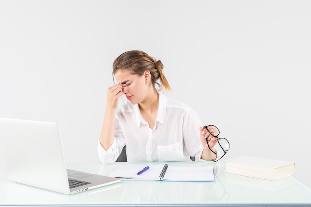 Free Photo young tired woman in front of a laptop at office desk, isolated on white background