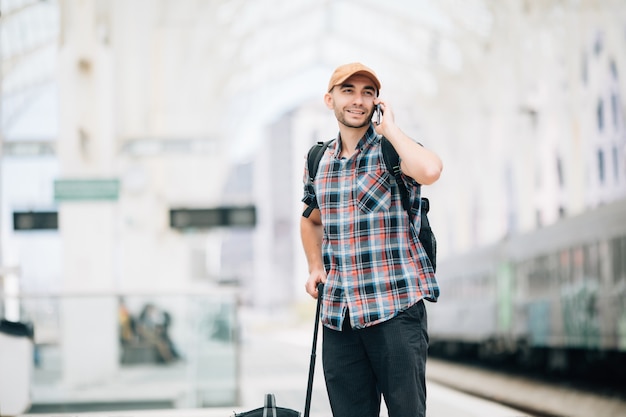 Free photo young traveler man talking on the phone at the train station