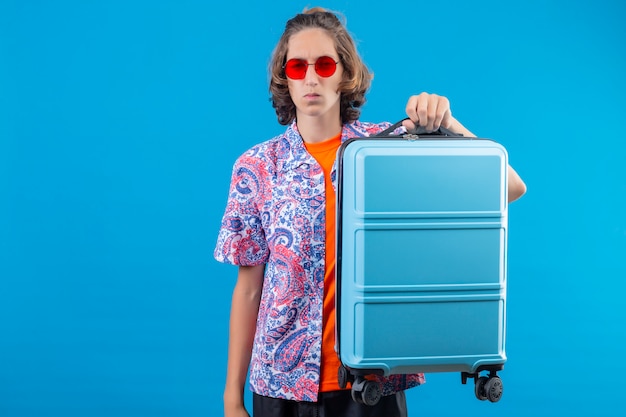 Free Photo young traveler man with suitcase holding air tickets looking confused standing