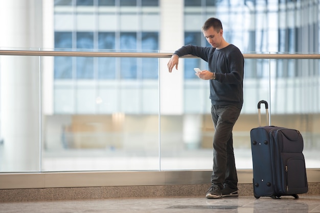 Free photo young traveler using smartphone in airport