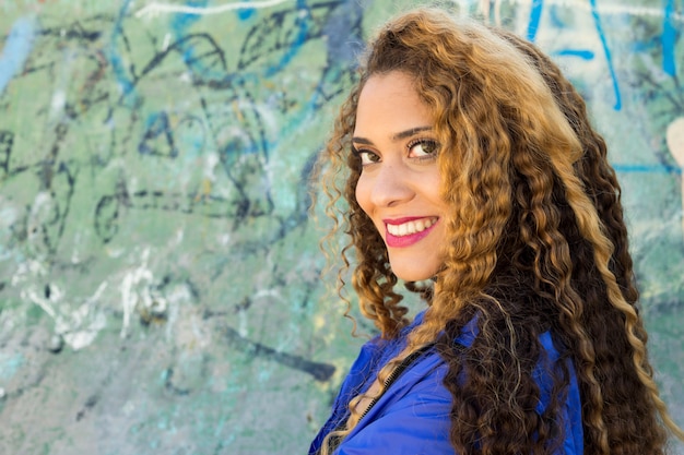 Young urban woman in front of graffiti wall