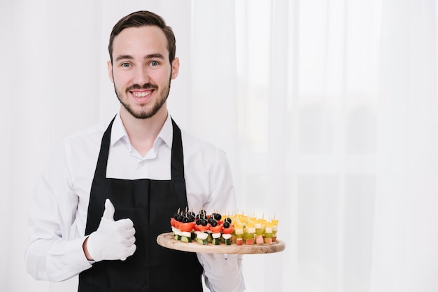 Young waiter showing appetizers 