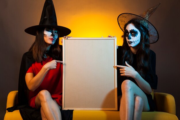 Young witches holding whiteboard