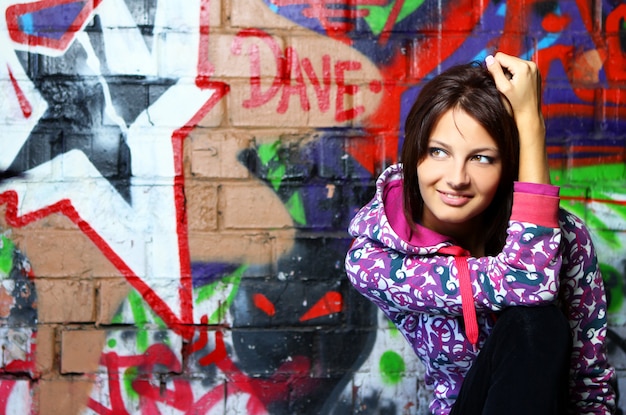 Free photo young woman against wall with graffiti