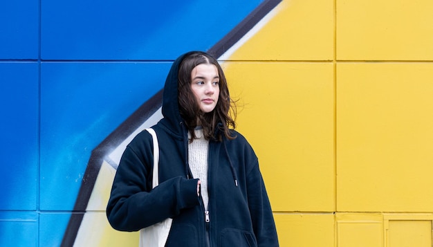 A young woman against a yellowblue wall urban graffiti