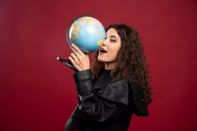 Young woman in all black outfit holding a globe.