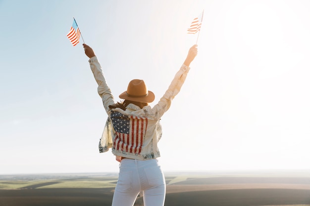 Free photo young woman in american flag jacket on top of mountain