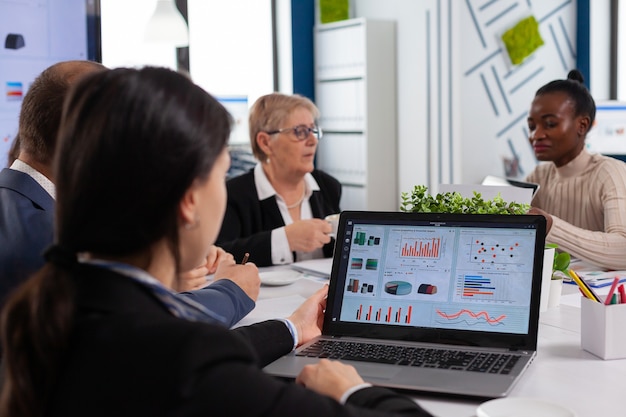 Young woman analysing charts on laptop in start up business meeting room