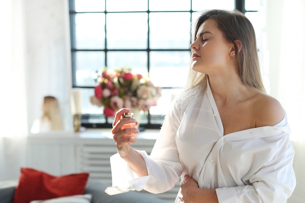 Free photo young woman applying perfume.