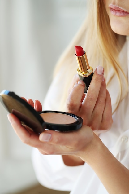 Young woman applying red lipstick.