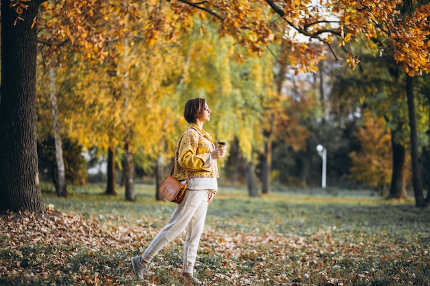 Free Photo young woman in an autumn park drinking coffee