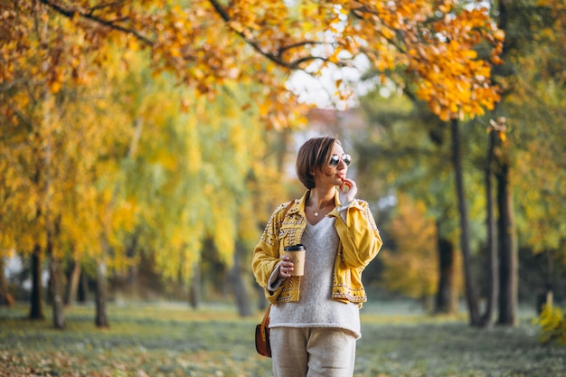 Young woman in an autumn park drinking coffee