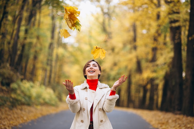 Free photo young woman in an autumn park throwing leaves