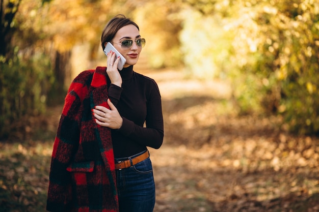 Young woman in autumn park using phone