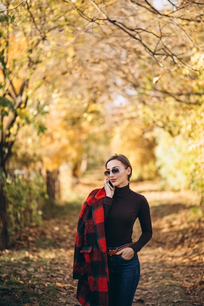 Young woman in autumn park using phone