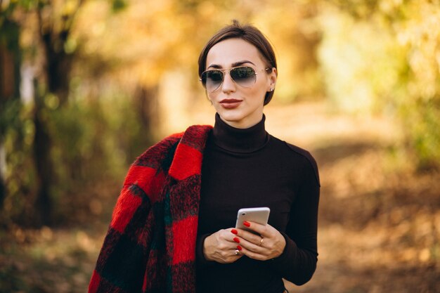 Young woman in autumn park using phone