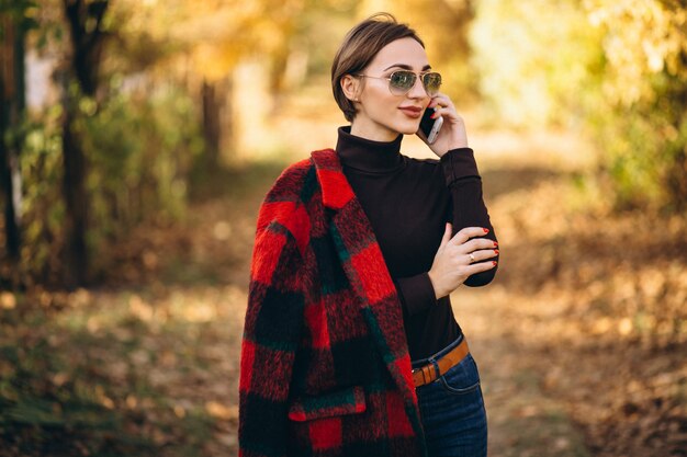 Young woman in autumn park using phone