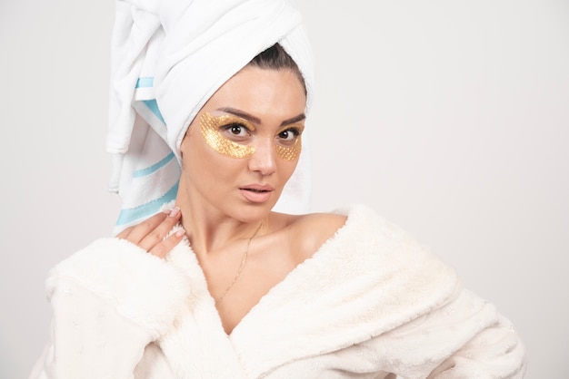 Young woman in bathrobe and cosmetic eye patches posing