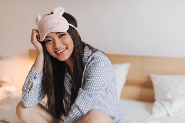 Young woman in beautiful sleeping mask with smile looks into front