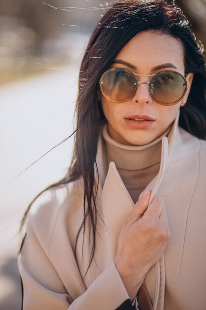 Young woman in beige coat walking in the street