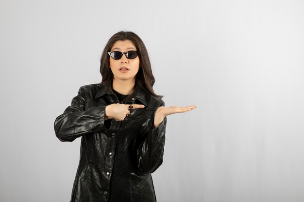 young woman in black coat wearing glasses and posing. 