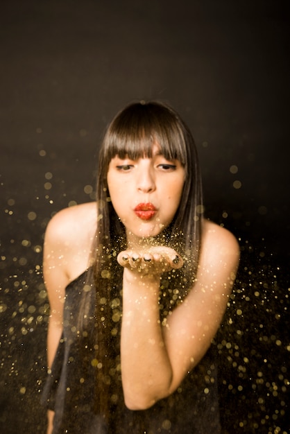 Free Photo young woman blowing confetti from palm