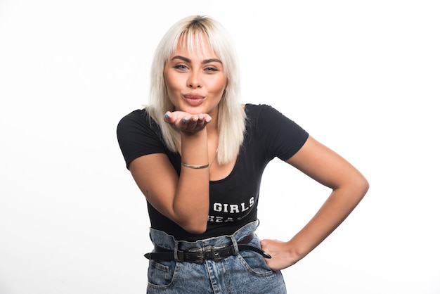 Free photo young woman blowing kiss on white wall.