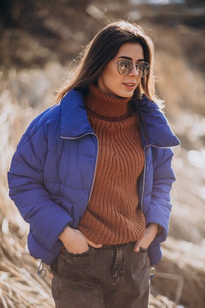 Young woman in blue jacket outside in park