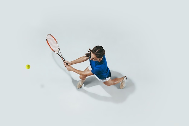 Young woman in blue shirt playing tennis. Indoor studio shot isolated on white. Top view.