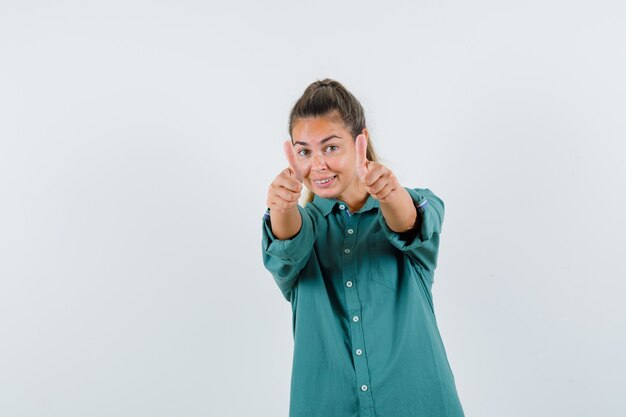 Young woman in blue shirt showing thumb up and looking joyful