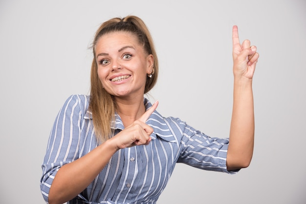 Young woman in blue sweater pointing at something.