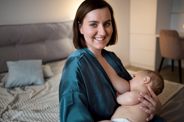 Free photo young woman breastfeeding her cute baby