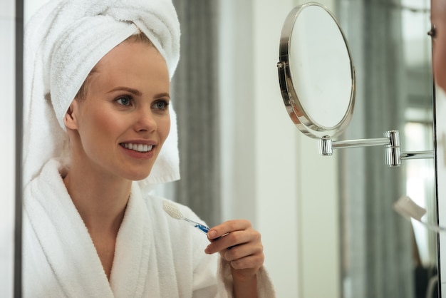 Young woman brushing teeth against mirror