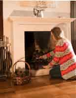 Free photo young woman burning fireplace with matchstick at home