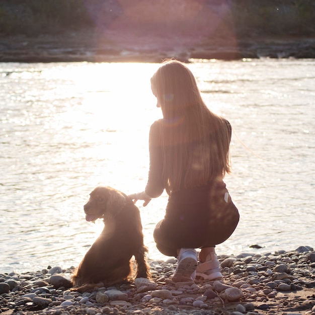 Free Photo young woman by the lake with her dog