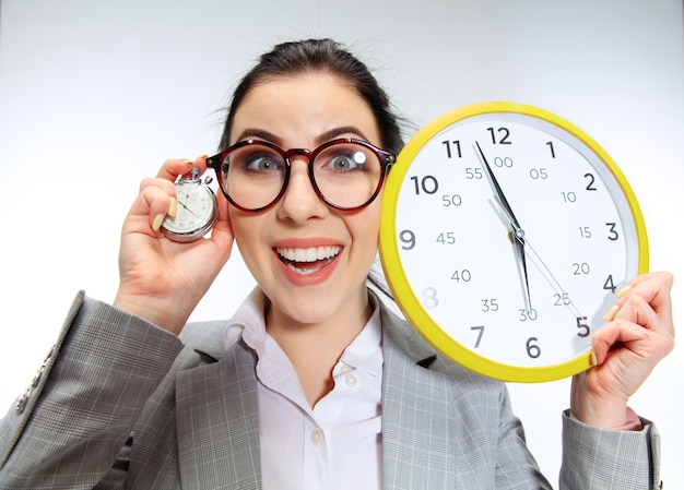 Free photo young woman can't wait to go home from the nasty office. holding the clock and waiting five minutes before the end. concept of office worker's troubles, business or problems with mental health.