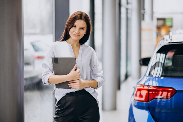 Young woman in a car showroom choosing a car