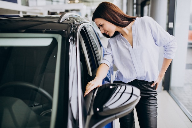 Free Photo young woman in a car showroom choosing a car