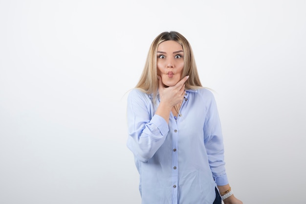 Young woman in casual outfit looking at camera on white wall