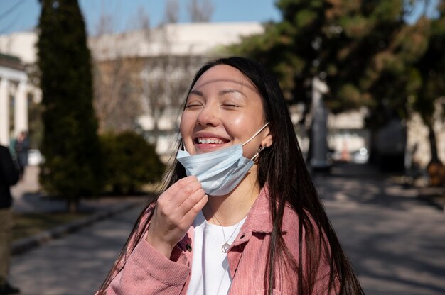 Young woman celebrating the lifting of face mask restrictions outdoors in the city