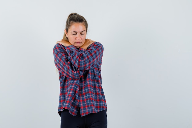 Free photo young woman in checked shirt standing arms crossed, shivering from cold and looking exhausted