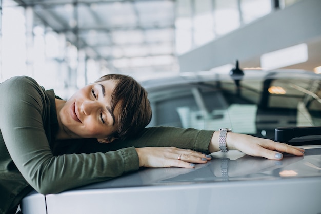 Free photo young woman choosimng a car in a car showroom