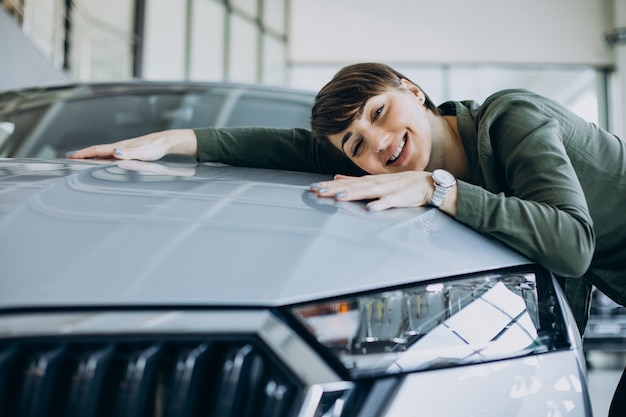 Young woman choosimng a car in a car showroom