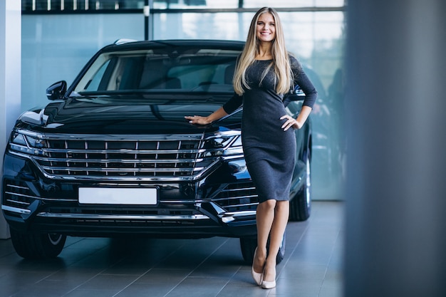 Young woman choosing a car in a car showroom