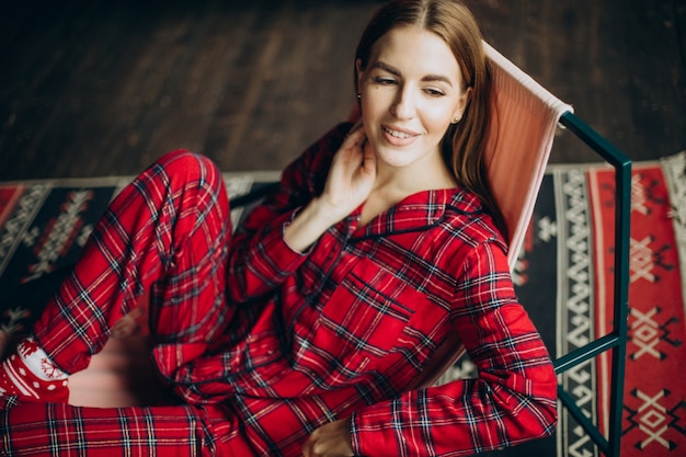 Free Photo young woman in christmas pyjamas sitting on chair