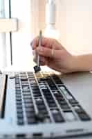 Free photo young woman cleaning her laptop key board