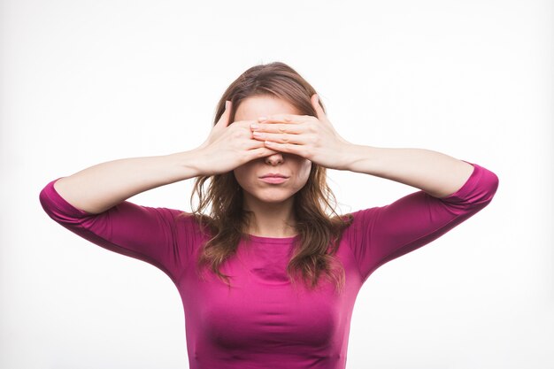 Young woman closing her eyes with two hands on white backdrop