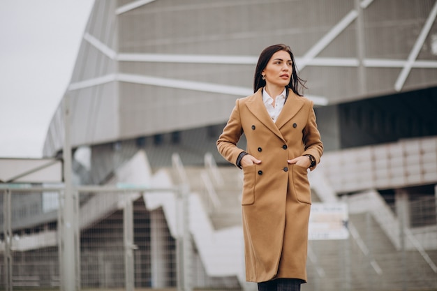 Free photo young woman in coat standing outdoors