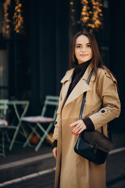 Young woman in coat walking by the cafe